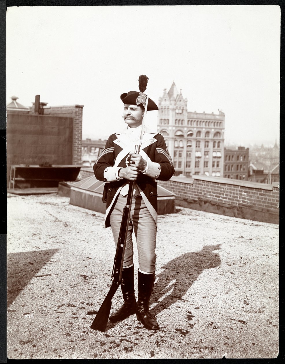Ein Mann auf einem Dach in traditioneller Militäruniform, hält ein Gewehr, 1895 von Byron Company