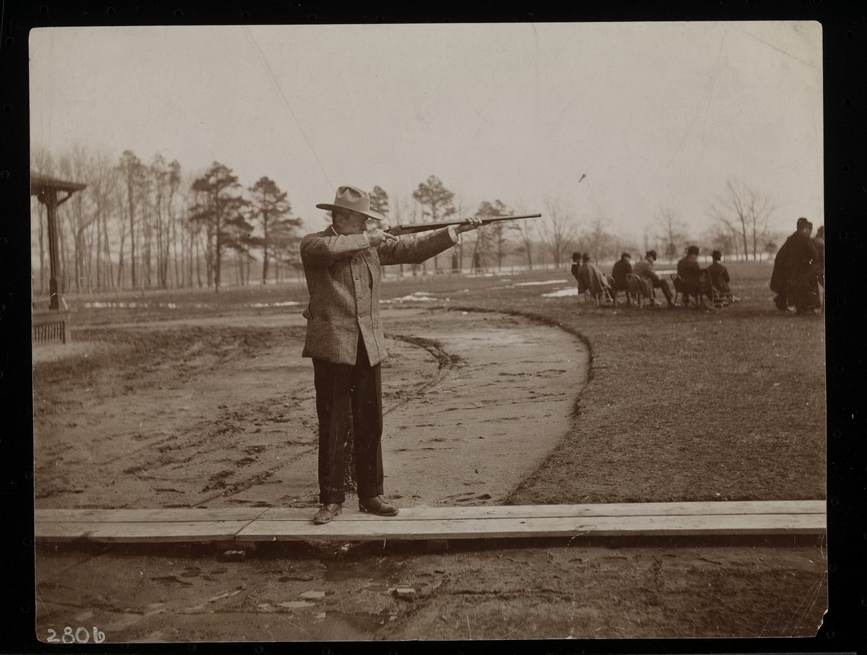Frank Work zielt mit einem Gewehr auf ein Tontaubenschießen, New York, 1896 von Byron Company