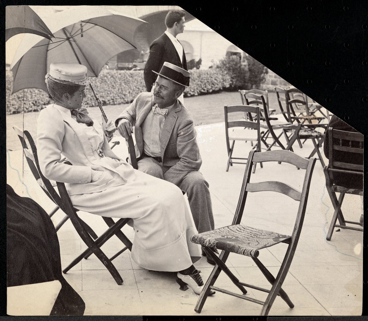 Mann und Frau sitzen draußen auf Klappstühlen, Frau hält einen Sonnenschirm, Narragansett, Rhode Island, 1891 von Byron Company