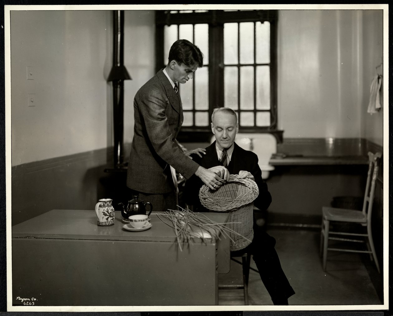 Mann unterrichtet einen anderen Mann im Korbflechten bei der New York Association for the Blind, 111 East 59th Street, New York, 1931 von Byron Company