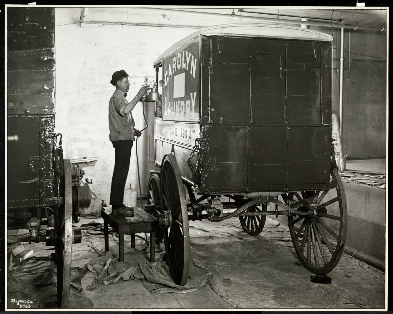 Ein Mann sprüht einen Lieferwagen der Carolyn Laundry in der 111 East 128th Street, East Harlem, New York, 1929 von Byron Company