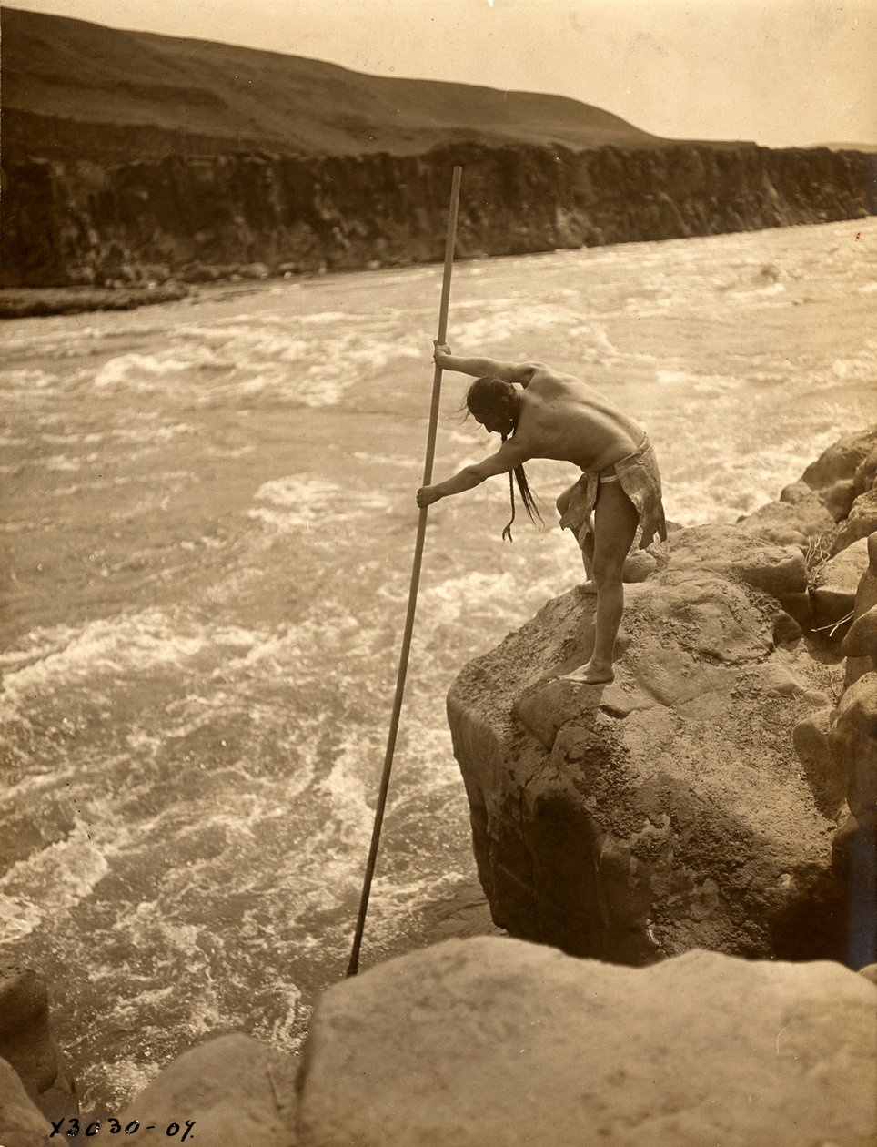 Tlakluit-Indianer, stehend auf Felsen, fischend mit Dip-Netz, ca. 1910 (s/w Foto) von Edward Sheriff Curtis