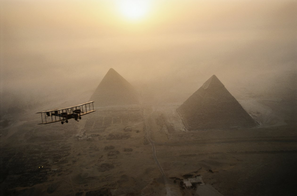 Das Vintage-Flugzeug Vimy fliegt über nebelverhüllte Pyramiden während eines goldenen Sonnenaufgangs von James L Stanfield