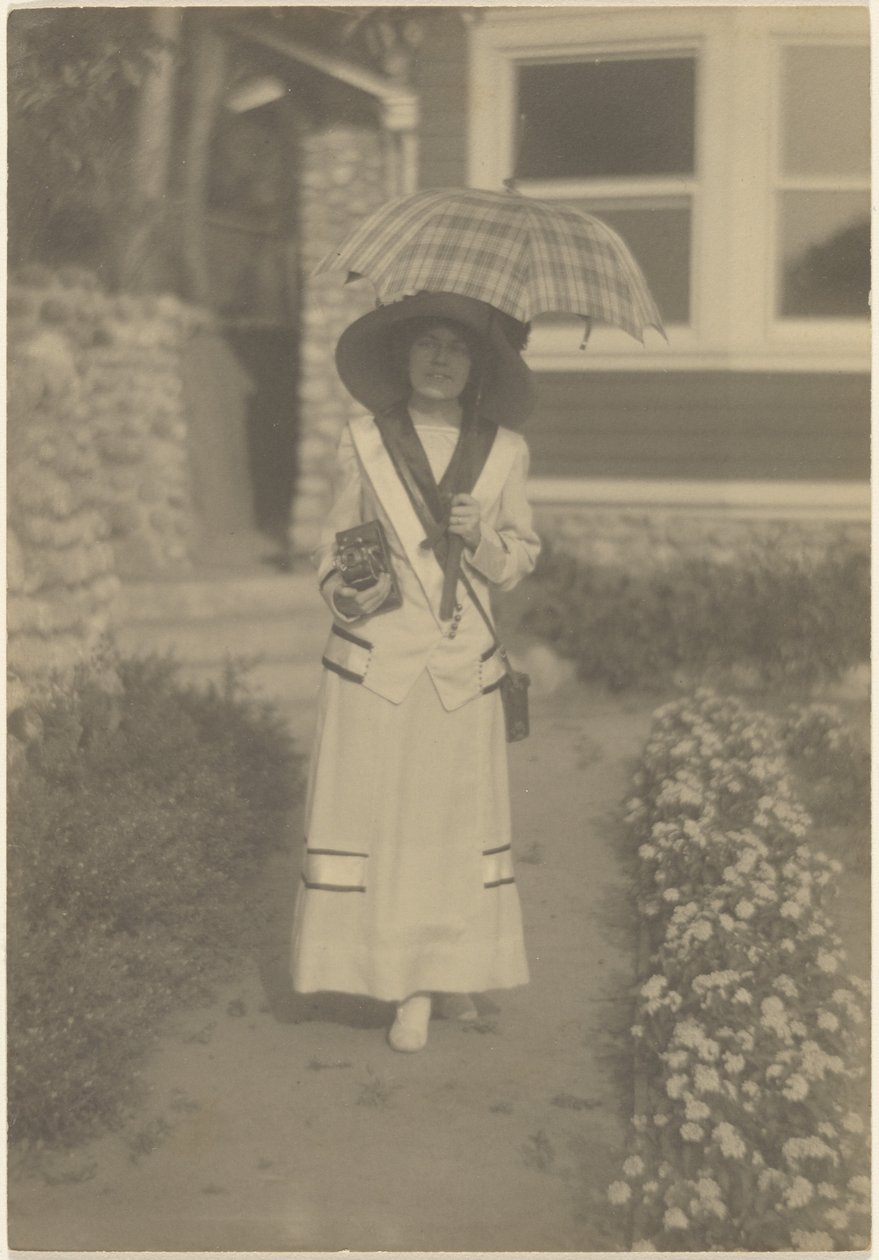 [Frau im Vorgarten mit Kamera und kariertem Regenschirm] von Louis Fleckenstein