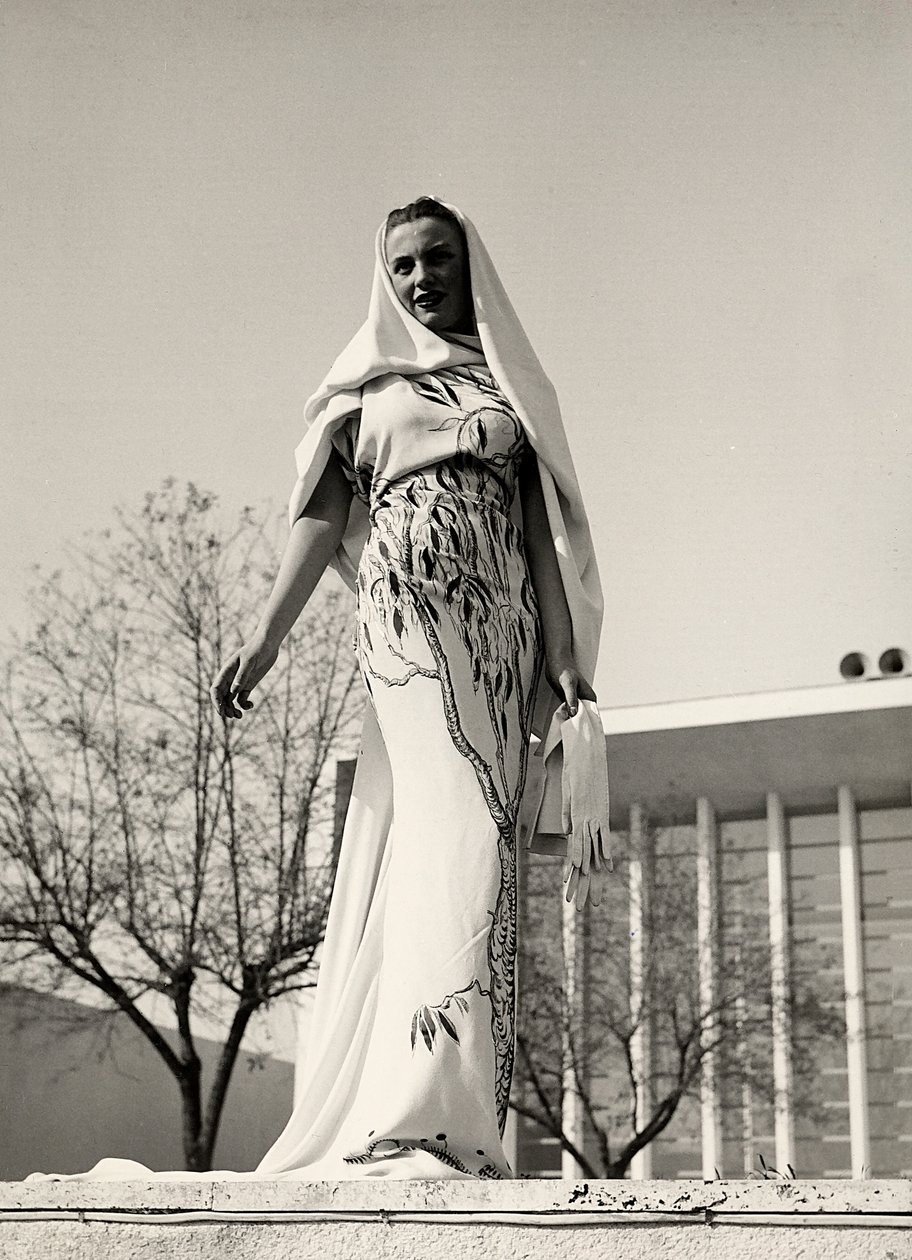 Modell in einem Abendkleid aus Blumenstoff, kreiert vom Modehaus "Lamma". Das Kleid wird mit einem langen Schleier ergänzt. von Luis Bogino