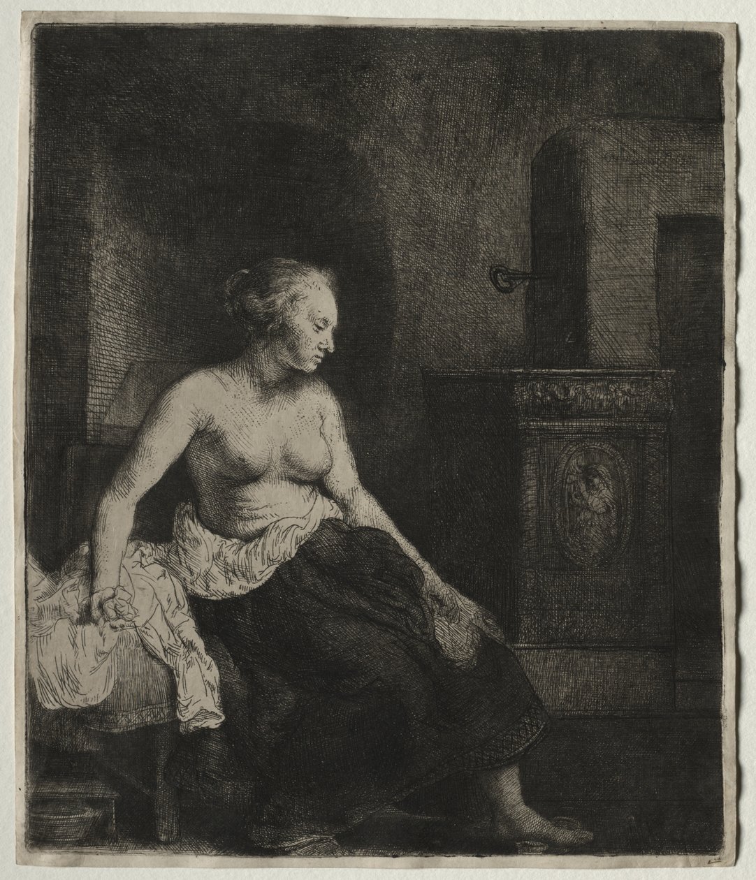 Frau sitzt halb angezogen neben einem Ofen von Rembrandt van Rijn
