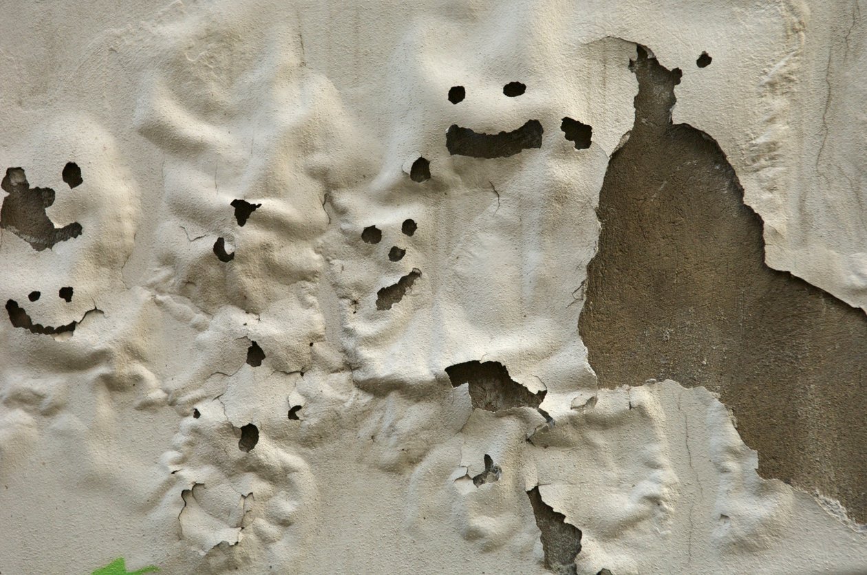 Italien, Toskana, Florenz, lächelnde Geistergesichter auf verwitterter bemalter Wand, 2022 (Foto) von Sisse Brimberg