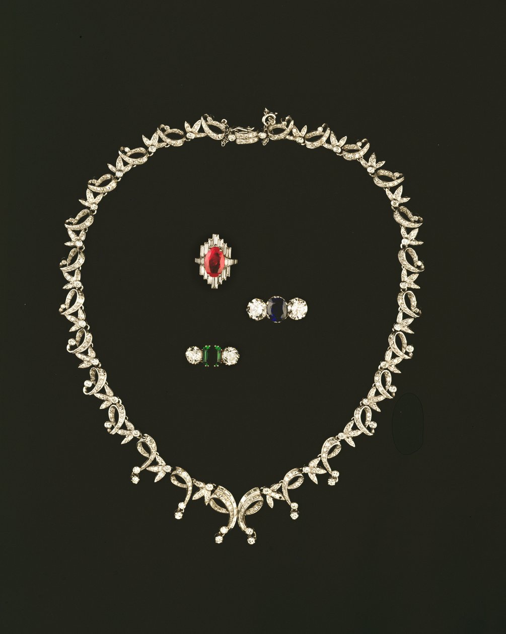 Art-Deco-Halskette mit Scroll- und Blattdesign; Rubin- und Diamant-Baguette-Cluster-Ring; Saphir- und Diamant-Dreistein-Ring; Smaragd- und Diamant-Dreistein-Ring von Unbekannt Unbekannt