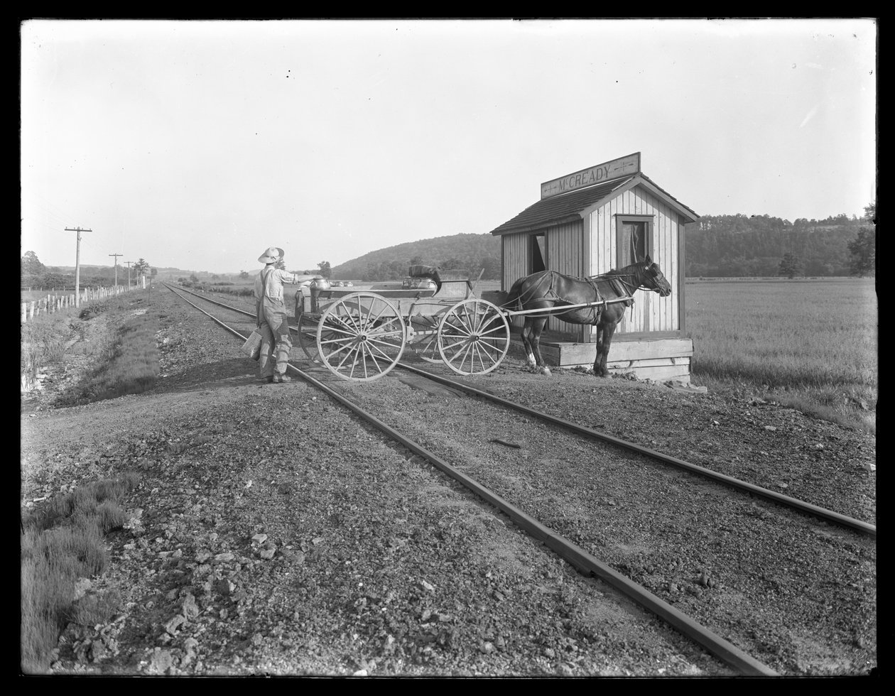 Unbekannter Mann lädt Milch auf einen pferdegezogenen Wagen, der über Eisenbahnschienen vor der McCready-Farm in Pennsylvania parkt, ca. 1913 von William Davis Hassler