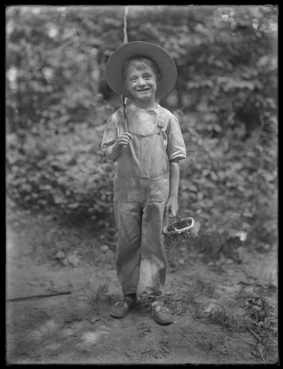 William Gray Hassler mit Strohhut und Latzhose, trägt Angelrute und Korb im Wald, 20. August 1911 von William Davis Hassler