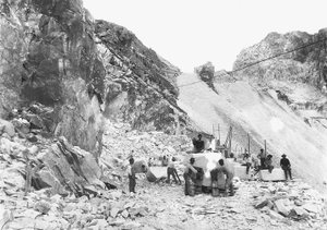 Ausgräber bei der Arbeit in einem Marmorbruch in den Apuanischen Alpen, Toskana. Einige von ihnen sitzen auf bereits quadratischen Marmorblöcken. von A. Corsini