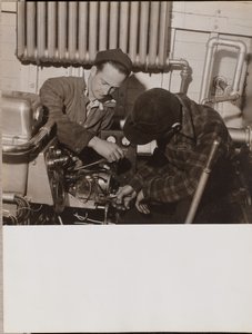 Zwei Männer arbeiten an einer Maschine mit Schraubenzieher und Schraubenschlüssel von Arnold Eagle