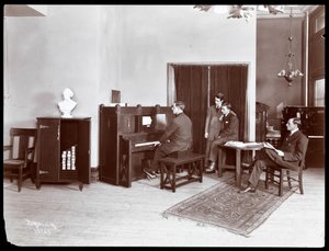 Vier Männer, einer spielt ein H. Bruman Co. Klavier, 1907 von Byron Company