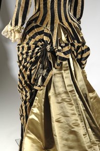 Abendkleid, ca. 1884 (schräge Rückansicht des Bustledetails). Seidensatin und geschnittener Samt, Spitze, Seidenfadenquasten und Fransen. Charles Frederick Worth, Frankreich. von Charles Frederick Worth