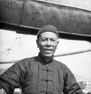 Porträt eines Besatzungsmitglieds einer Salz-Dschunke aus Kanton an Bord seines Schiffes in Sham Shui Po, Hongkong von David Watkin Waters