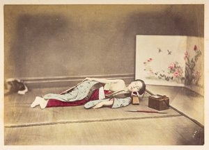 Japanische Frau schläft, Studio-Porträt einer jungen japanischen Frau, die schläft, eine Brust entblößt und mit dem Kopf auf einem Holzpolster ruhend