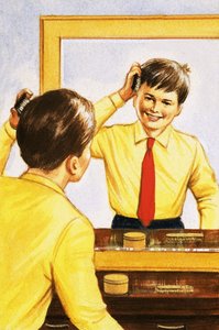 Junge, der sich vor einem mit einer dünnen Silberschicht hinterlegten Spiegel die Haare bürstet von English School