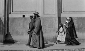 Russisch-orthodoxer Priester spaziert auf dem Bürgersteig, gefolgt von seiner Frau und zwei Kindern in Moskau