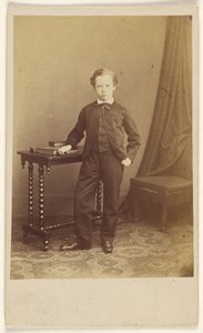 [Unidentifizierter kleiner Junge im Anzug an einem Tisch mit Büchern]
