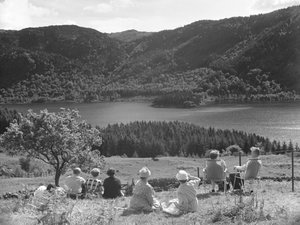 Gruppe von Menschen sitzt auf Gras oder Liegestühlen und schaut auf eine Aussicht von Thirlmere von Joseph Hardman