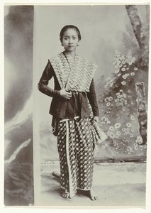 Studio-Porträt einer jungen javanischen Frau in einem Sarong mit Batikmuster und einem Hemd mit Karomuster