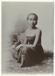 Studio-Porträt einer sitzenden jungen javanischen Frau in einem Sarong mit Batik-Muster