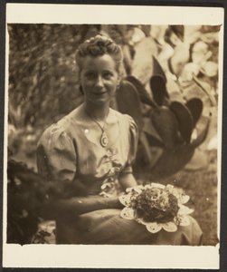 [Frau mit Blumenstrauß vor Kaktus sitzend]