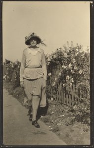 [Frau geht entlang eines Zauns mit Blumen]