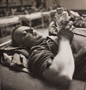 Militärischer Genesender betrachtet eine kleine Flasche mit einer chemischen Zubereitung von Luigi Leoni
