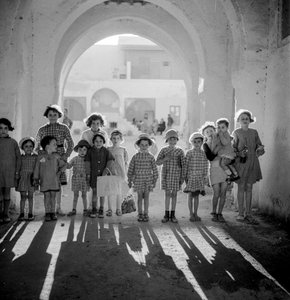 Europäische Kinder in Schuluniform unter einem Bogen mit Schatten.