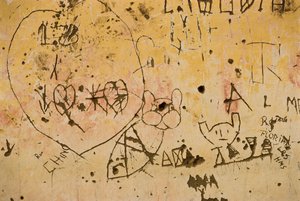 Graffiti in eine alte Außenputzwand eingeritzt.