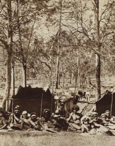 Australische Aborigines, die sich hinter einem Windschutz verstecken
