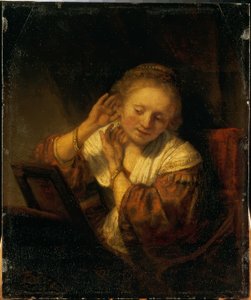 Junge Frau, die sich mit Ohrringen schmückt von Rembrandt van Rijn