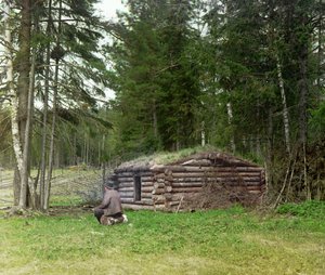Ein Mann vor einer Hütte für Holzfäller und Kuria (Kohlebrennen) im Wald, Russisches Reich, zwischen 1905 und 1915