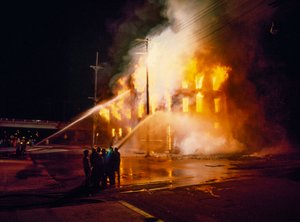 Ein städtisches Gebäude vollständig in Flammen in Kansas City bei Nacht mit Feuerwehrleuten