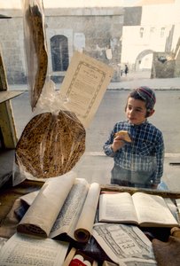 Konservativer jüdischer Junge isst Kuchen und schaut in eine religiöse Buchhandlung