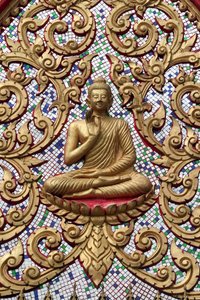 Eingangstür verziert mit Goldreliefs. Der lehrende Buddha zeigt einen besonderen Moment im Leben des Buddha, nämlich die erste Predigt nach der Erleuchtung
