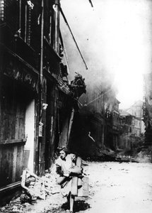 Eine Frau verlässt ihr brennendes Haus in einer bombardierten Straße, Deutschland, 1945