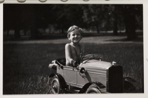 Junge fährt ein Spielzeug-Tretauto, um 1930