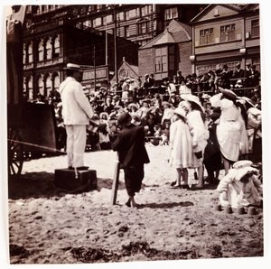 Menschenmenge beobachtet einen Strandunterhalter, um 1905 von Unbekannt