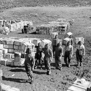 Ein Verpflegungslager und Männer, die mehr Vorräte dorthin tragen, März 1943