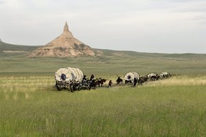 Geschichte der West-Eroberungssiedler: Amerikanische Pioniere. Reisen mehrerer Familien, die die Ebenen der Vereinigten Staaten in Kutschen überqueren. Kutschen überqueren den Chimney Rock auf dem Oregon Trail, Nebraska. Farbige Gravur kombiniert mit ein von Unbekannter Künstler