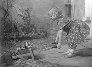Kleines Mädchen spielt mit einer Schubkarre. Fotografie um 1931