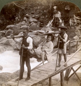 Japanische Frau in einem Yamakago-Bergstuhl überquert den reißenden Daiya-Fluss in der Nähe von Nikko, Japan