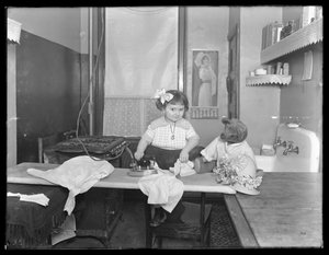 Unidentifiziertes kleines Mädchen, das die Verwendung eines elektrischen Bügeleisens demonstriert, c.1913-14
