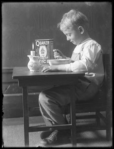William Gray Hassler sitzt an einem kleinen Tisch und isst eine Schüssel Quaker Puffreis, ca. 1912