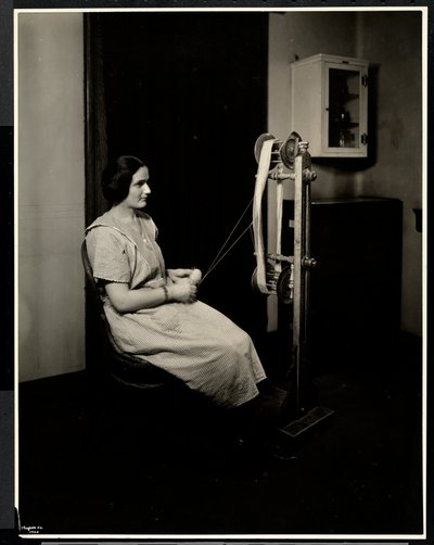 Porträt einer blinden, tauben und stummen jungen Frau beim Spinnen von Wolle in der New York Association for the Blind, 111 East 59th St., New York, 1923 von Byron Company