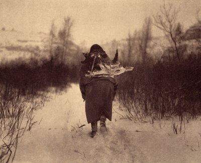 Zum Lager gehen. Ein Apsaroke-Indianer trägt Holz im Schnee, in einem kleinen Winterlager in der Nähe eines Baches in den Pryor Mountains, Montana. Foto aus Band 4 der Enzyklopädie von Edward S. Curtis (1868-1952) über die Indianer Nordamerikas, mit von Edward Sheriff Curtis
