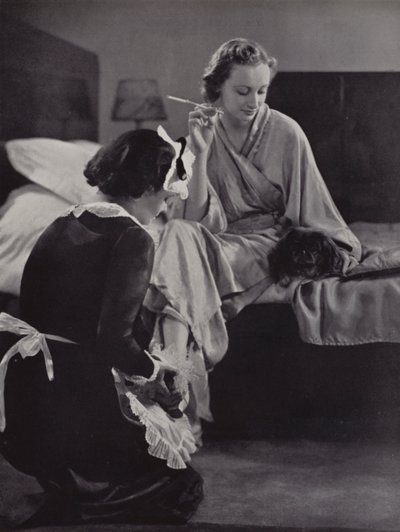 Frau wird morgens von ihrer Zofe beim Ankleiden geholfen, Mayfair, London von English Photographer
