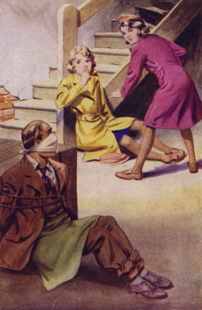 Ein gefesselter und geknebelter Mann sitzt auf dem Boden, während zwei Mädchen zuschauen von English School